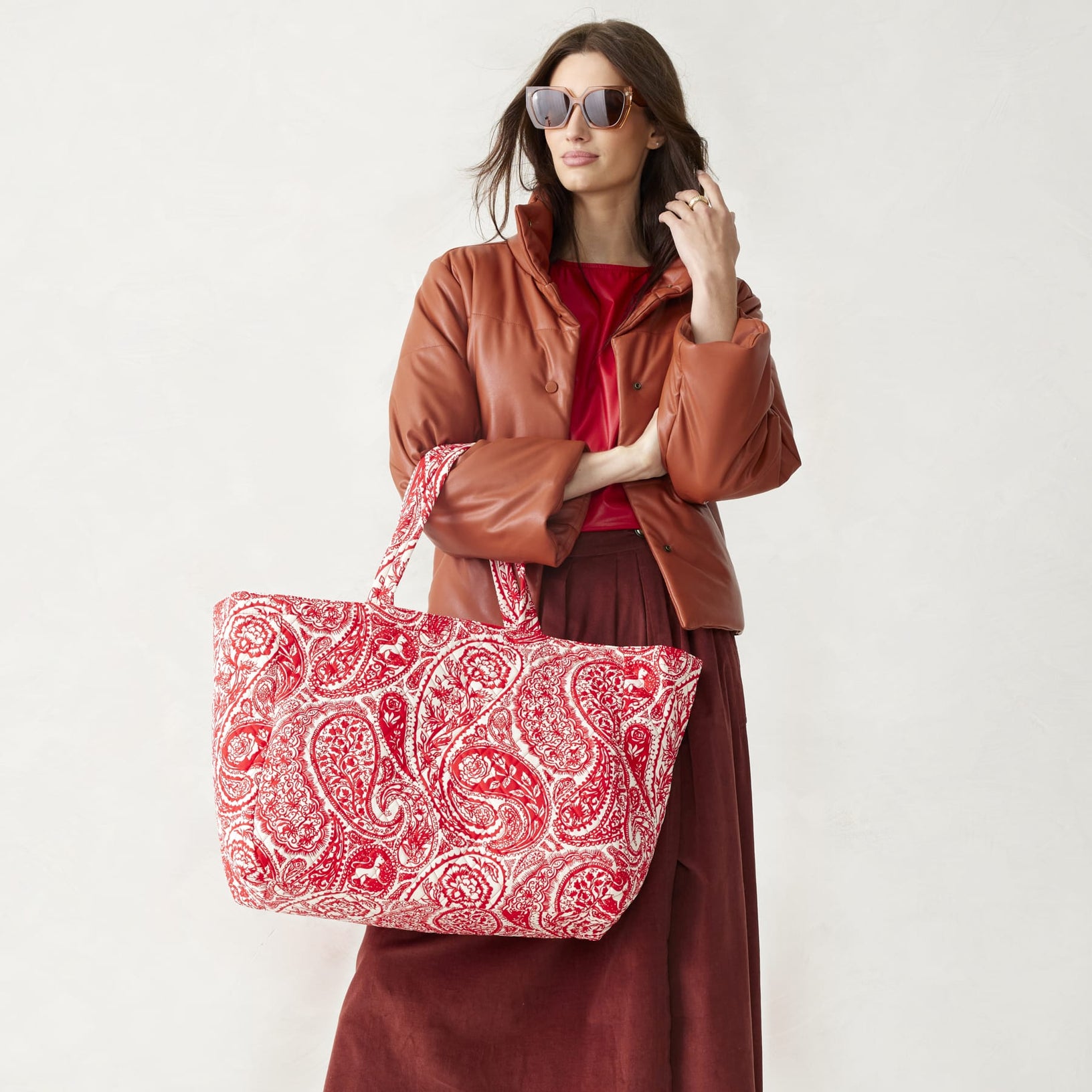 model wearing sunglasses and holding a large red and white paisley cotton travel tote bag