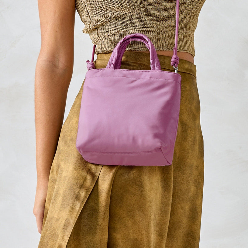 model holding green crossbody wallet purse with tomato pattern against denim pants