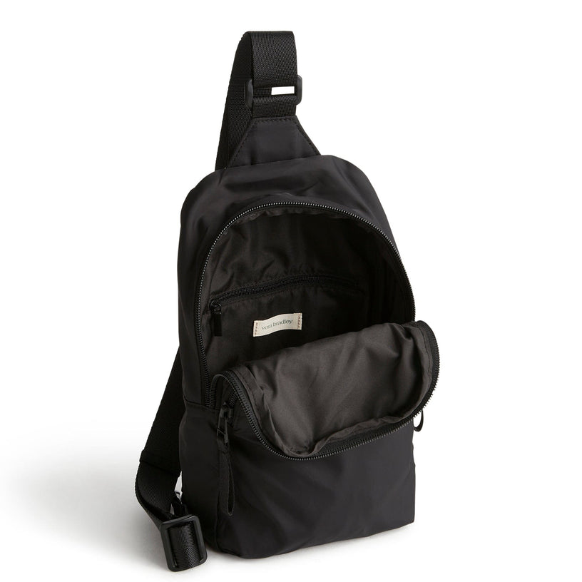Black sling backpack with front zipped open to show interior compartment