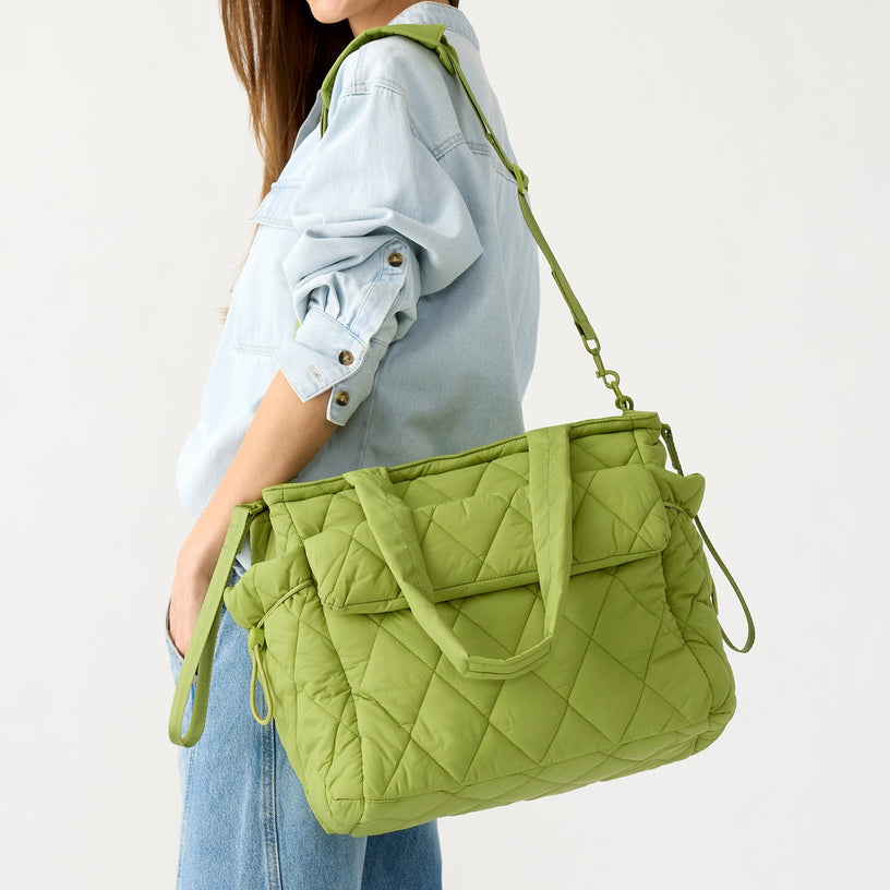 model holding green quilted diaper bag tote